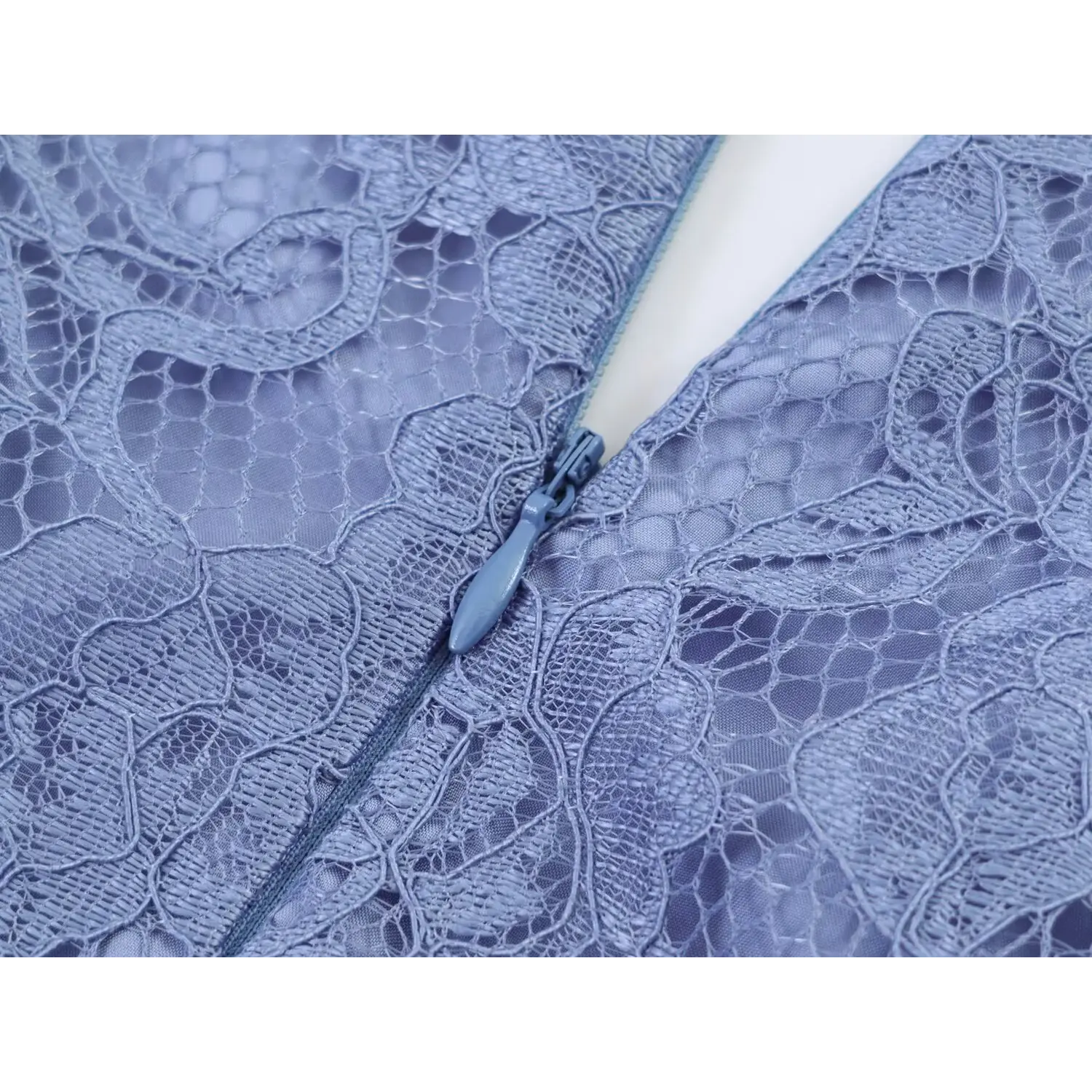 Extreme close‑up of back zipper pull surrounded by floral lace dusty blue maxi dress