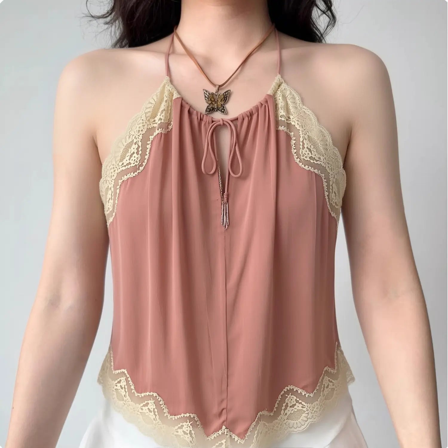 Front lifestyle shot on model of dusty pink halter cami top, front keyhole cutout, cream lace trim, irregular wavy hem
