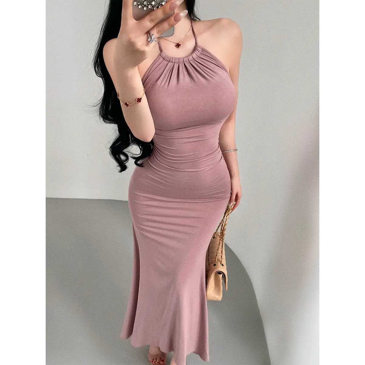 Close-up of a woman wearing a dusty pink halter-neck mermaid maxi dress, showing the ruched halter neckline and bodycon fit.