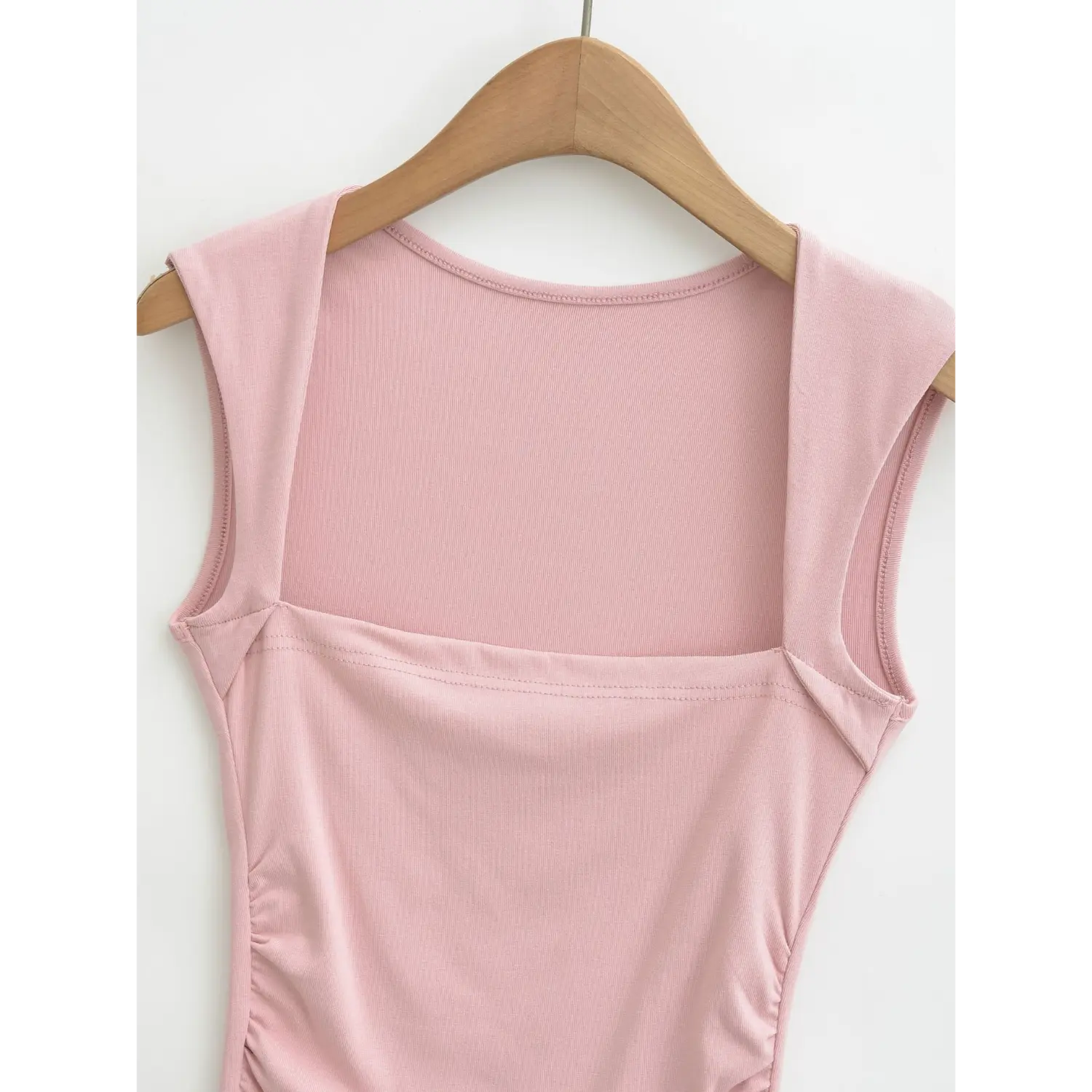 Close-up shot of square front neckline on dusty pink ribbed tank top, wide shoulder strap stitching detail