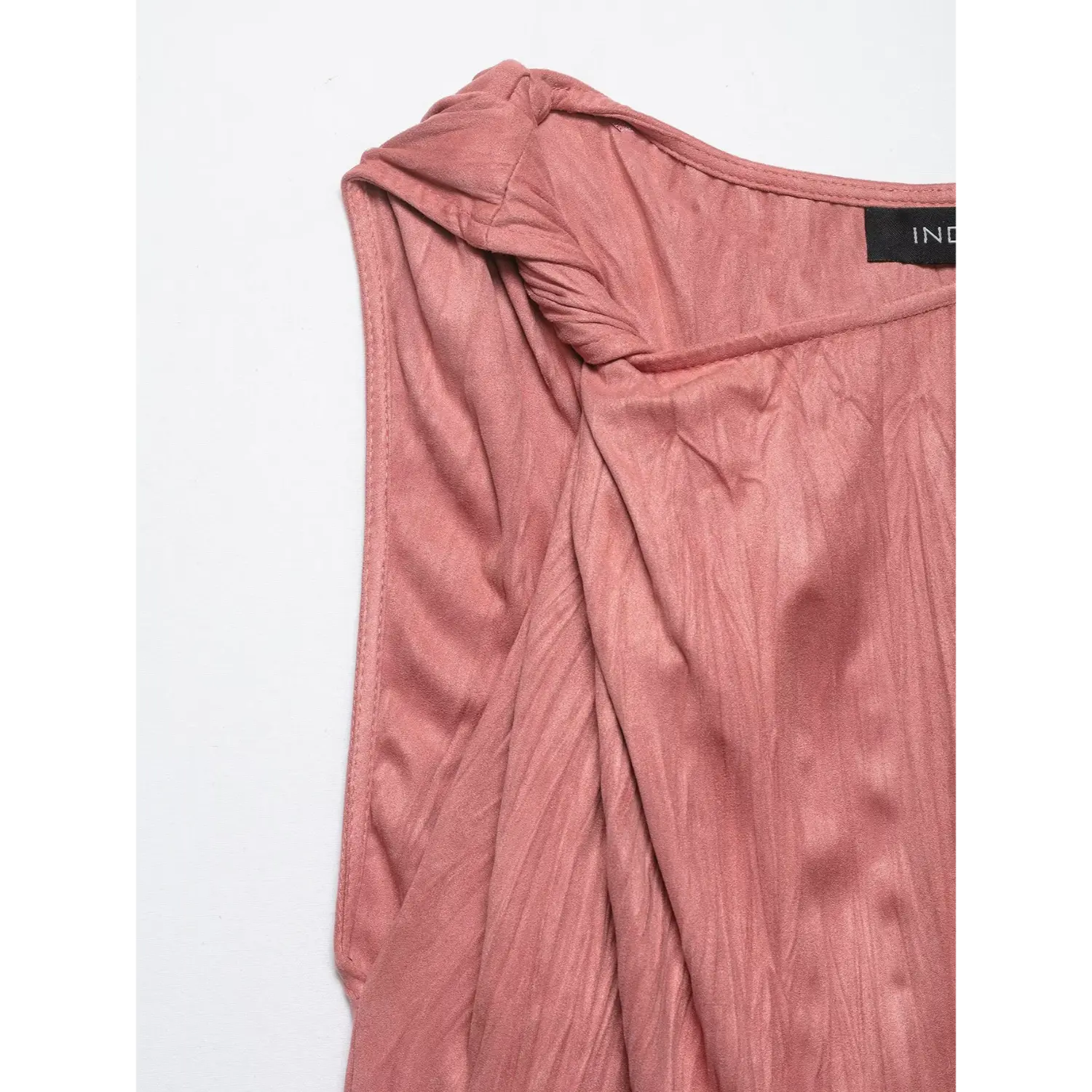 Close-up of twist shoulder detail and inner label on dusty rose crinkled satin sleeveless top
