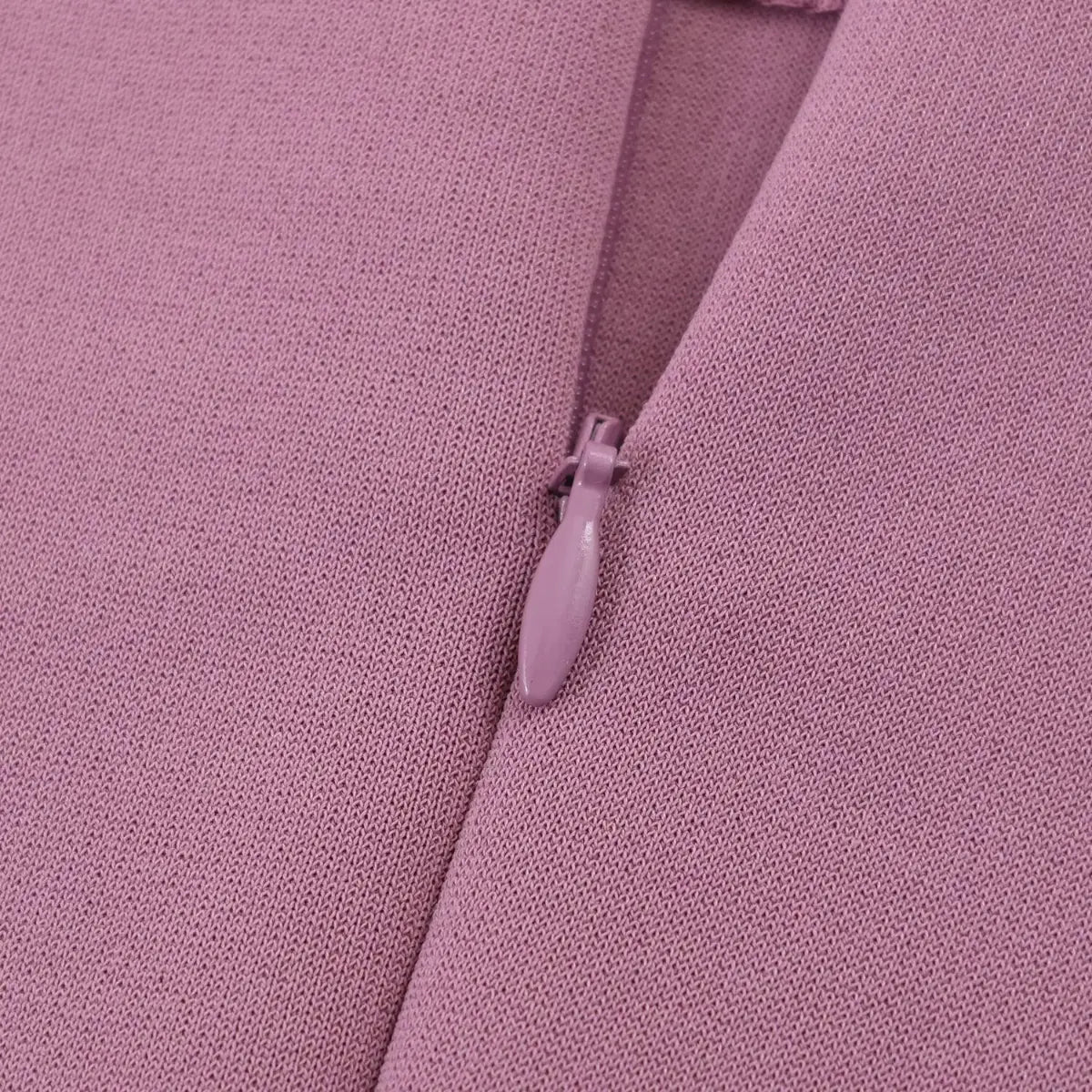 Close-up of the dress's hidden back zipper, featuring a matching dusty rose pull tab and smooth fabric texture.