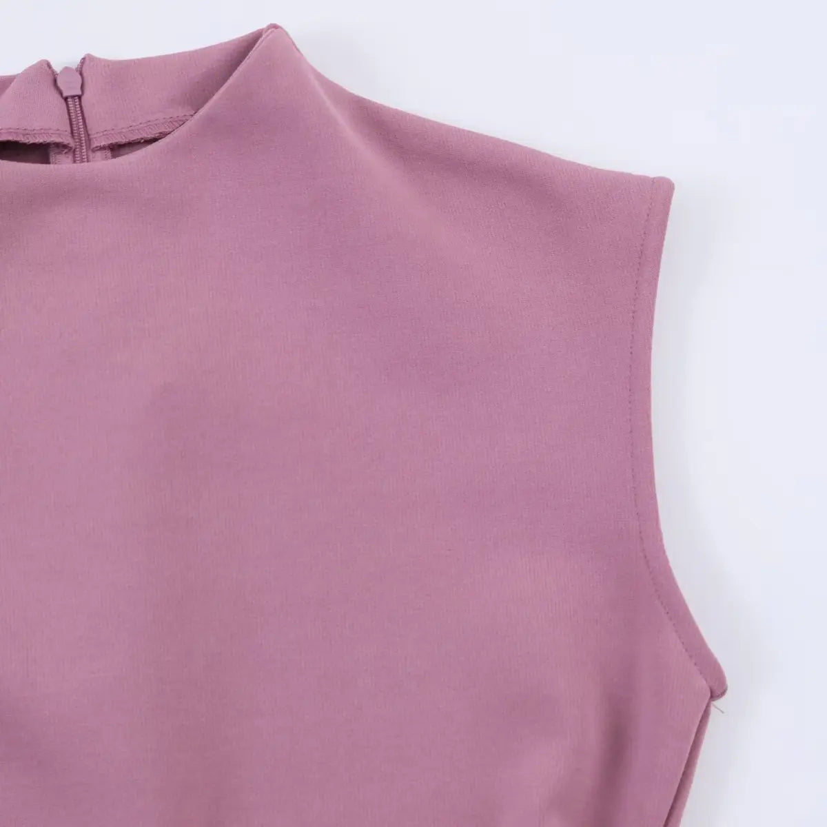 Close-up of the dress's high neckline and cap sleeve, showing the fine knit fabric, clean armhole stitching, and back zipper opening.