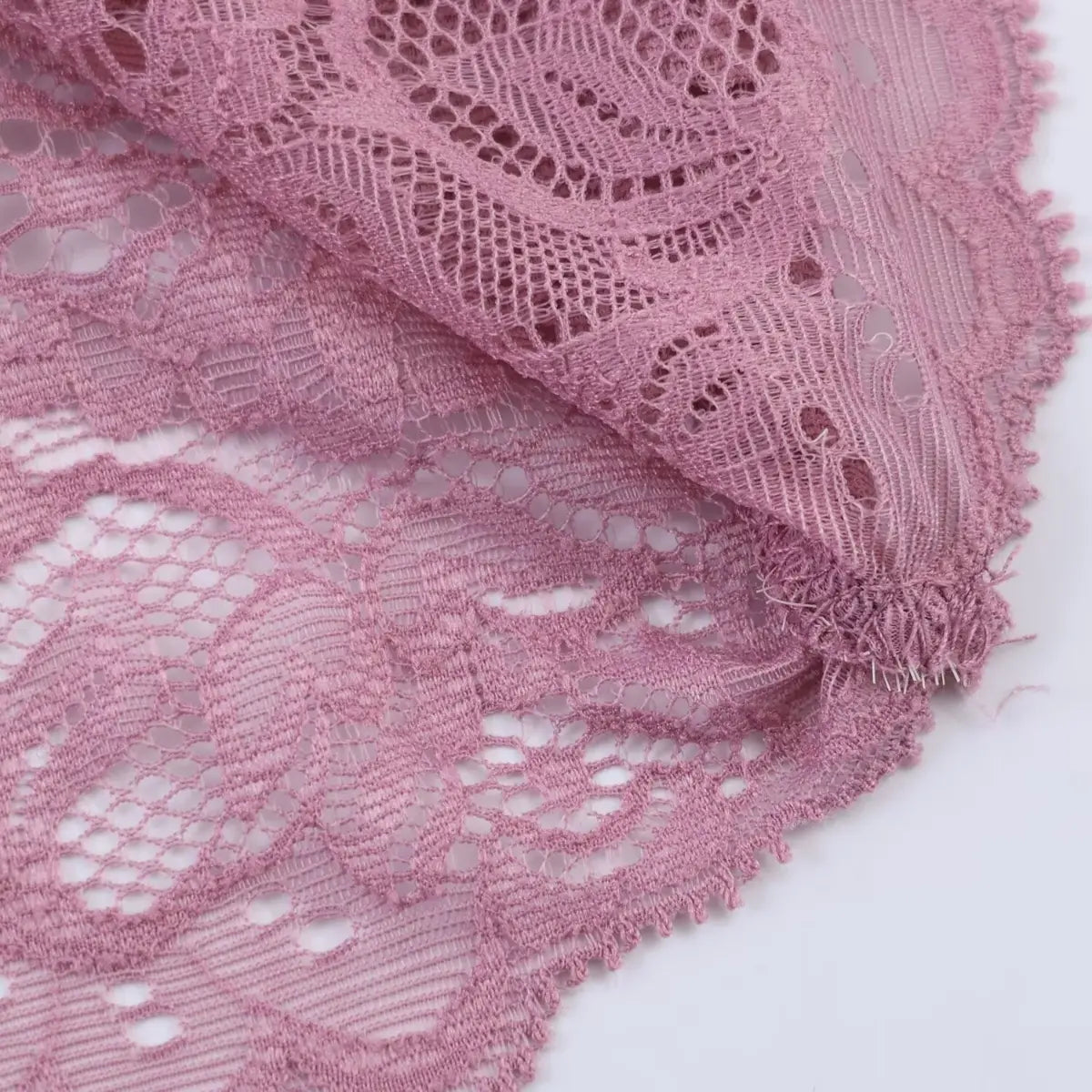 Close-up of the dress's lace overlay, showing the delicate floral pattern, openwork, and the soft, frayed edge finish.