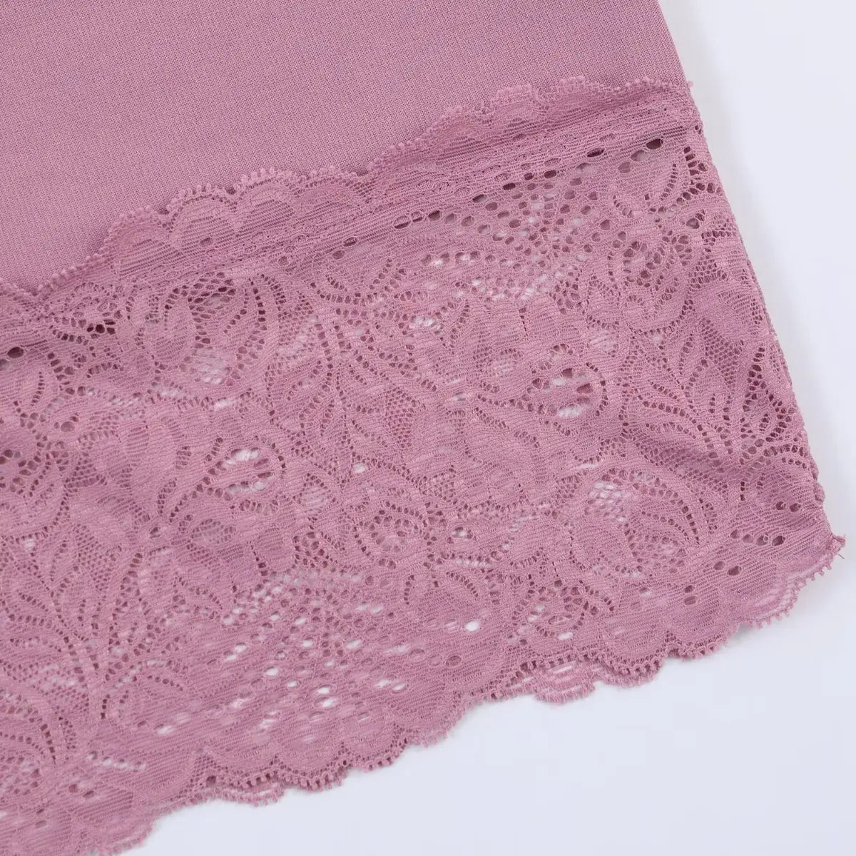 Corner close-up of the dress's lace hem, revealing the intricate openwork pattern, layered construction, and scalloped edge.