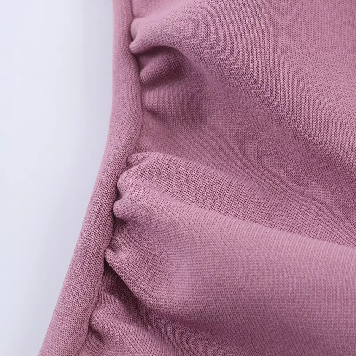 Close-up of the dress's side ruching, showing the gathered fabric detail that creates a cinched silhouette.