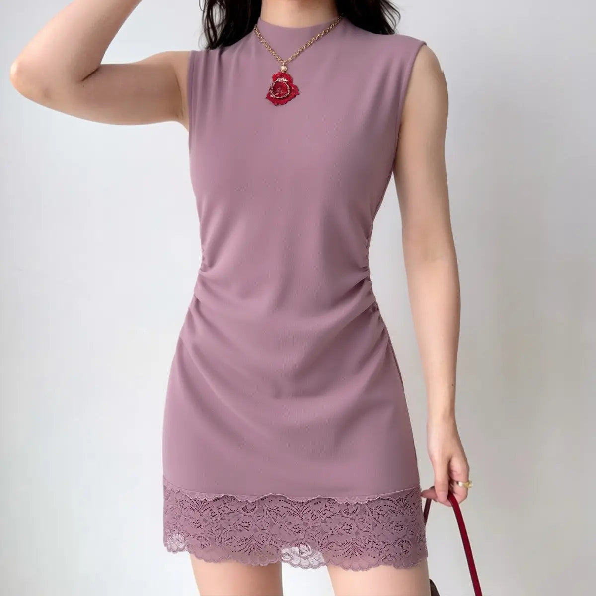 The dusty rose lace-trimmed dress styled on a model, highlighting its bodycon fit, high neckline, and elegant lace hem detail.