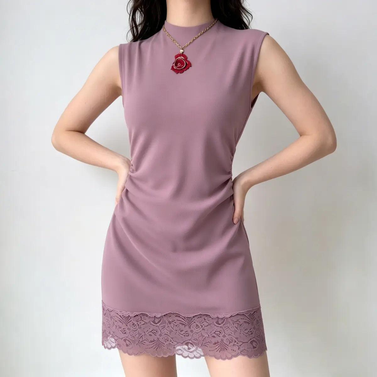 Model wearing a dusty rose sleeveless mini dress with a lace hem, featuring a high neckline, side ruching, and form-fitting silhouette.