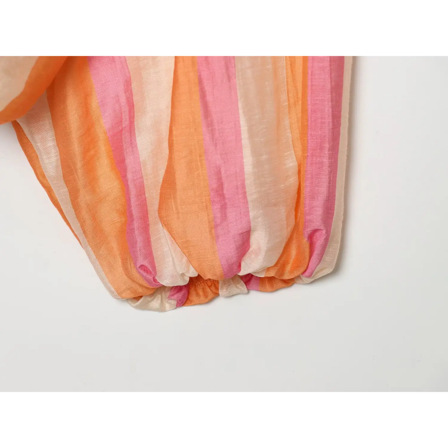 Sleeve cuff close-up, gathered elastic cuff, soft wrinkled lightweight fabric, orange pink vertical stripes