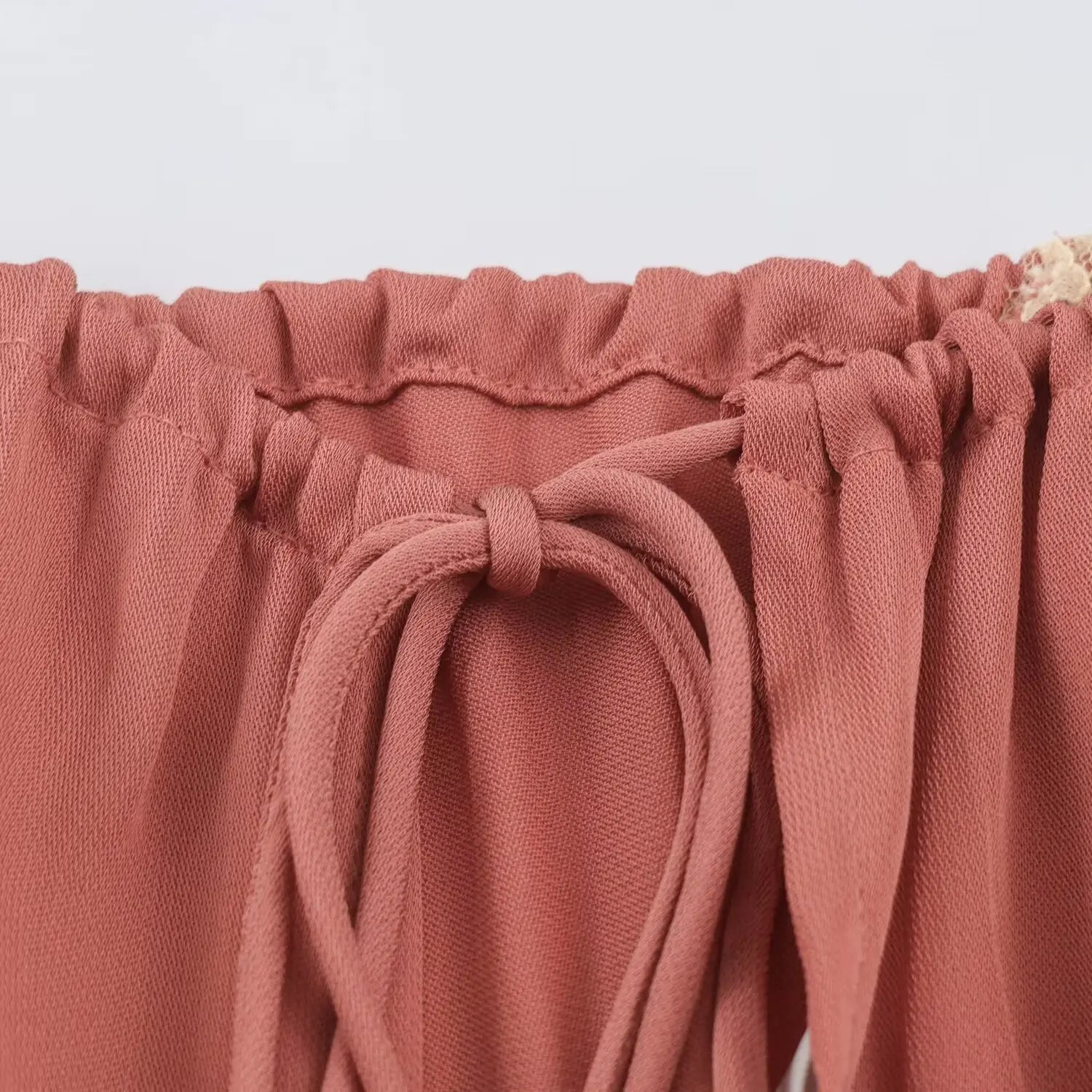 Closeup of elastic shirred halter neck and adjustable fabric drawstring