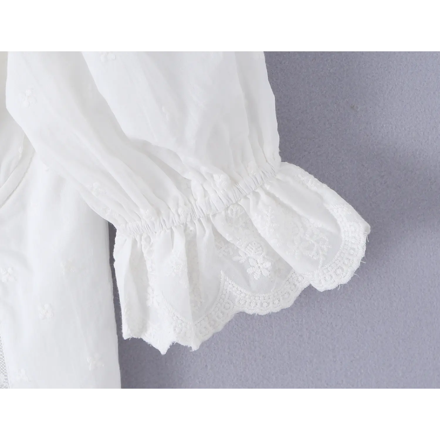 Close up elasticated puff sleeve cuffs with scalloped floral lace frill white eyelet crop blouse