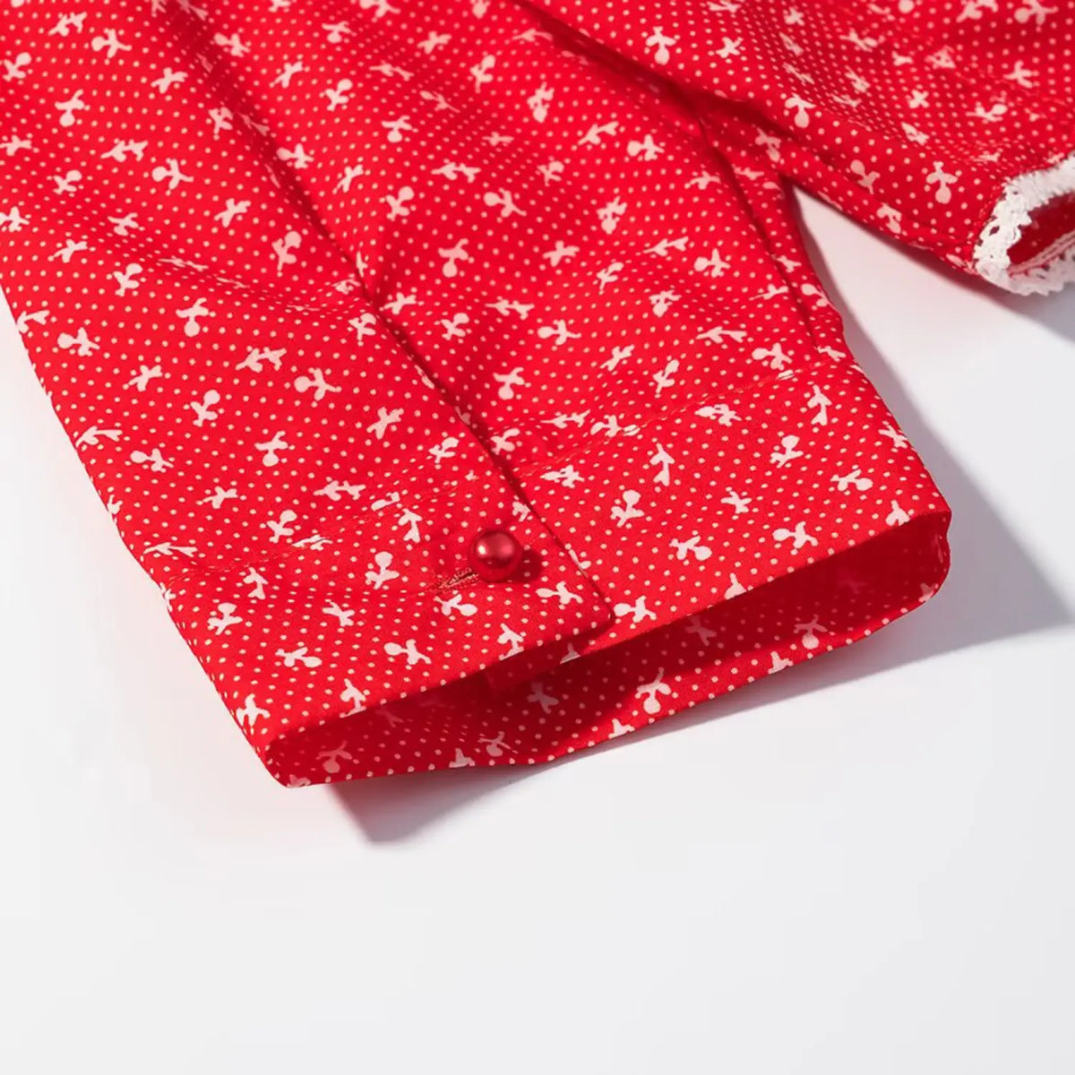 Detail of elbow sleeve cuff with small red pearl button closure