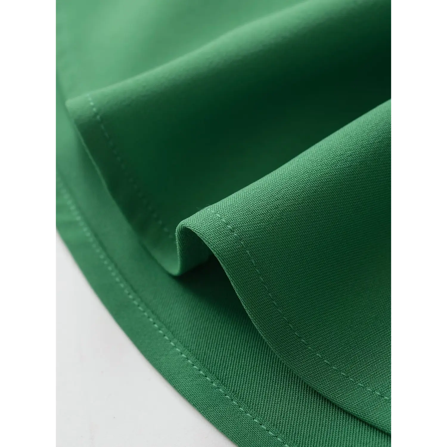 Macro view of double-stitched hem on emerald green smooth crepe fabric
