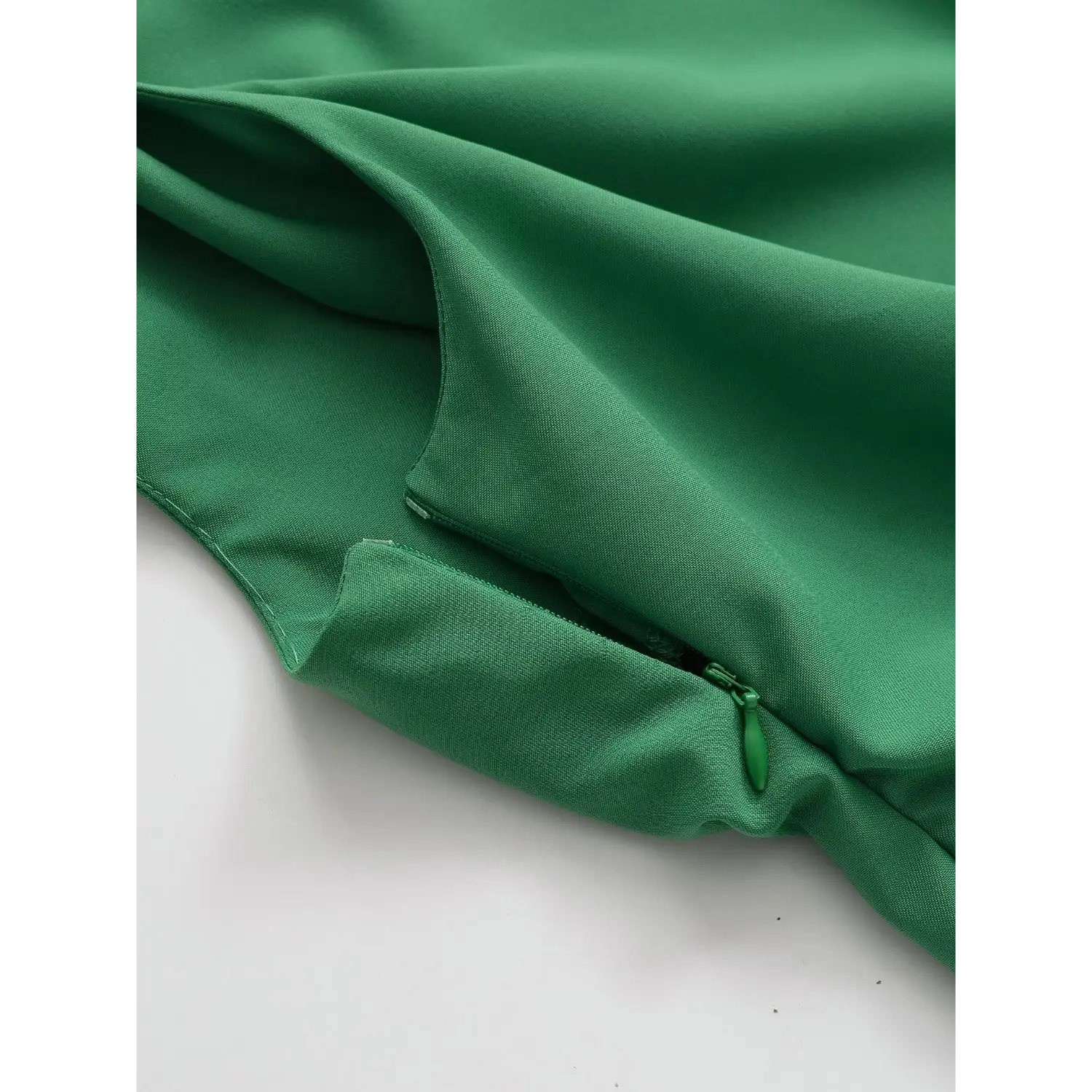 Close-up detail of side invisible zipper on emerald green crepe one-shoulder top