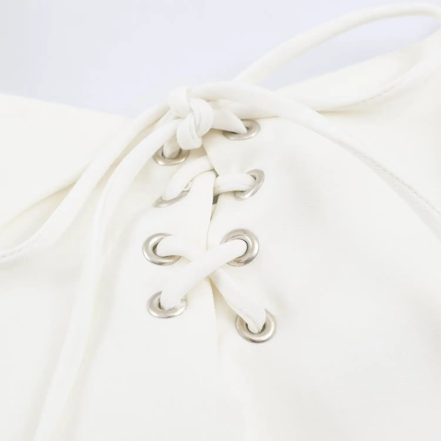 Extreme closeup silver metal eyelet and fabric tie detail for front corset lace-up