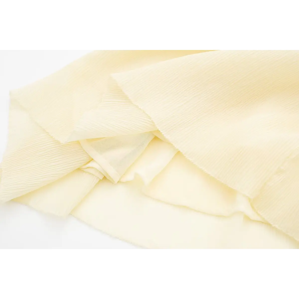 Close-up of the crinkled fabric and opaque lining on a cream smocked cami dress, highlighting the texture and layering.