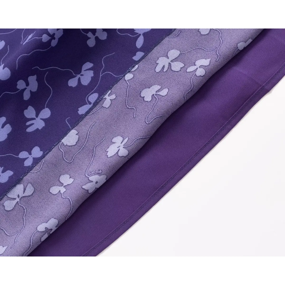  Close-up of the fabric and inner lining of a purple floral print dress, highlighting the semi-sheer overlay and opaque lining.