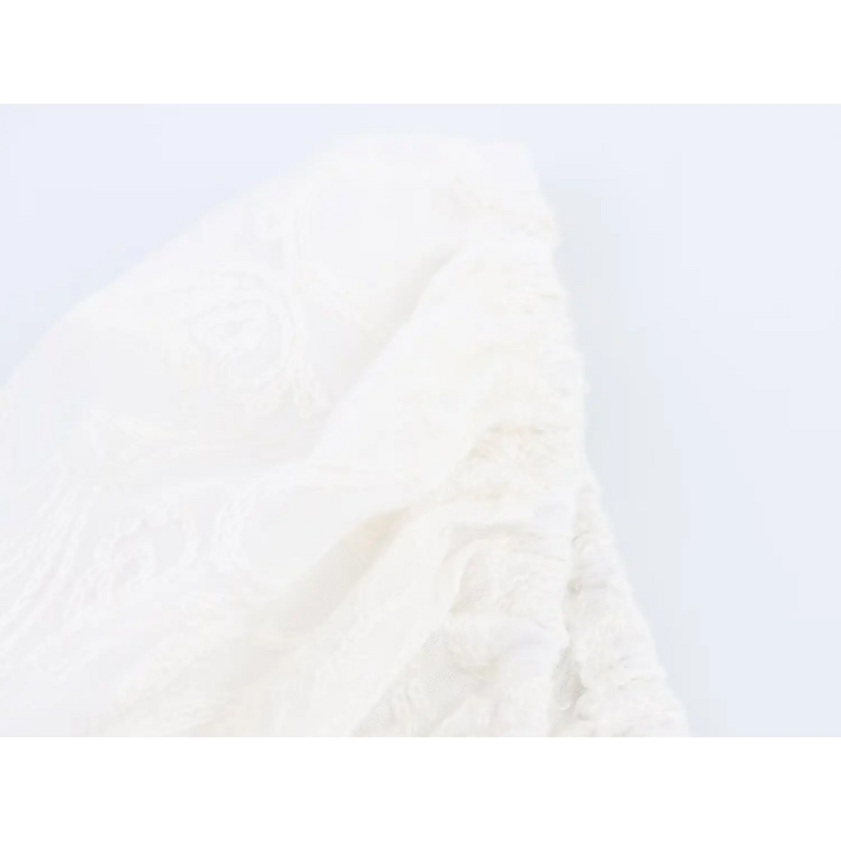 Macro shot of white paisley jacquard fabric texture and raised embroidery details