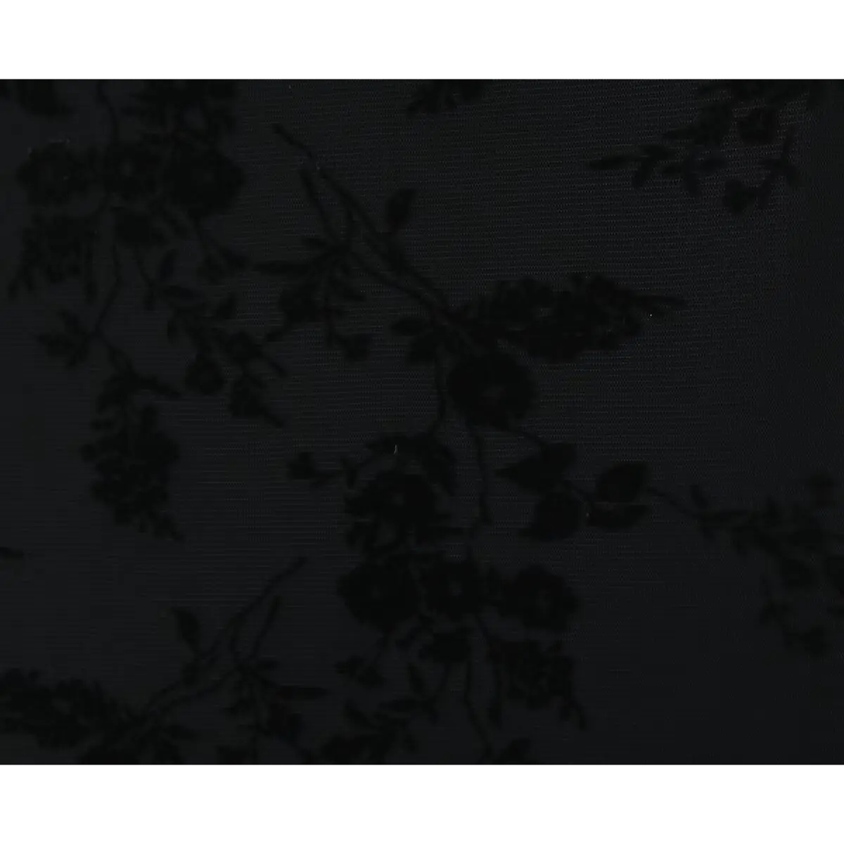 Close-up of the fabric texture on a black slip dress, showcasing the velvet floral flocking on sheer mesh