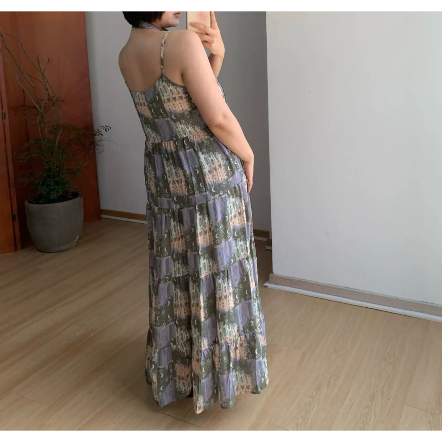 Back side indoor mirror shot of vintage printed tier maxi slip dress, thin single adjustable spaghetti strap, plain open back, full multi-layer ruffle tier flowy swing skirt, muted olive lavender castle moon collage print lightweight drape fabric display, burgundy flat shoes