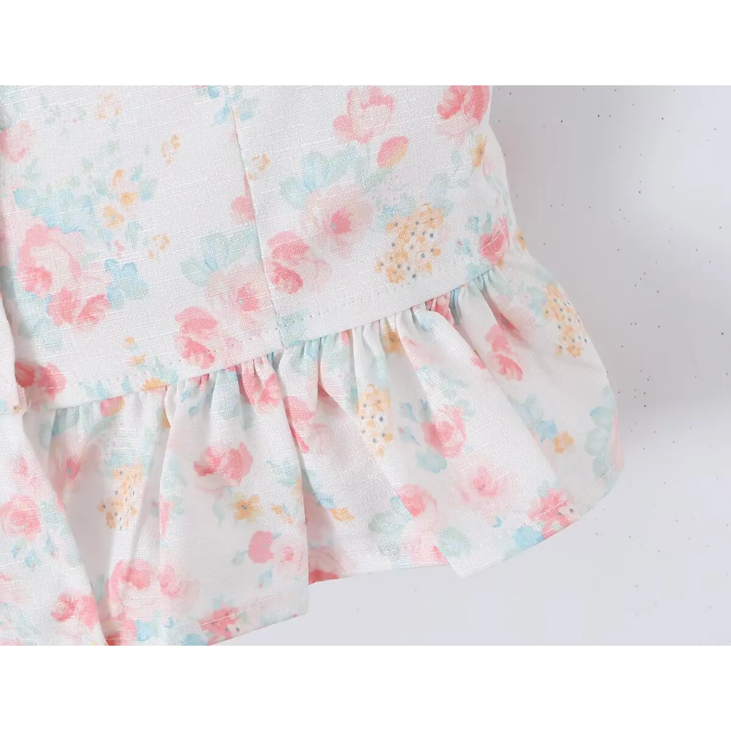Waist hem transition close-up gathered flared peplum ruffle, double layer lightweight floral fabric, matching color serged stitching, fitted waist silhouette against smocked stretch back