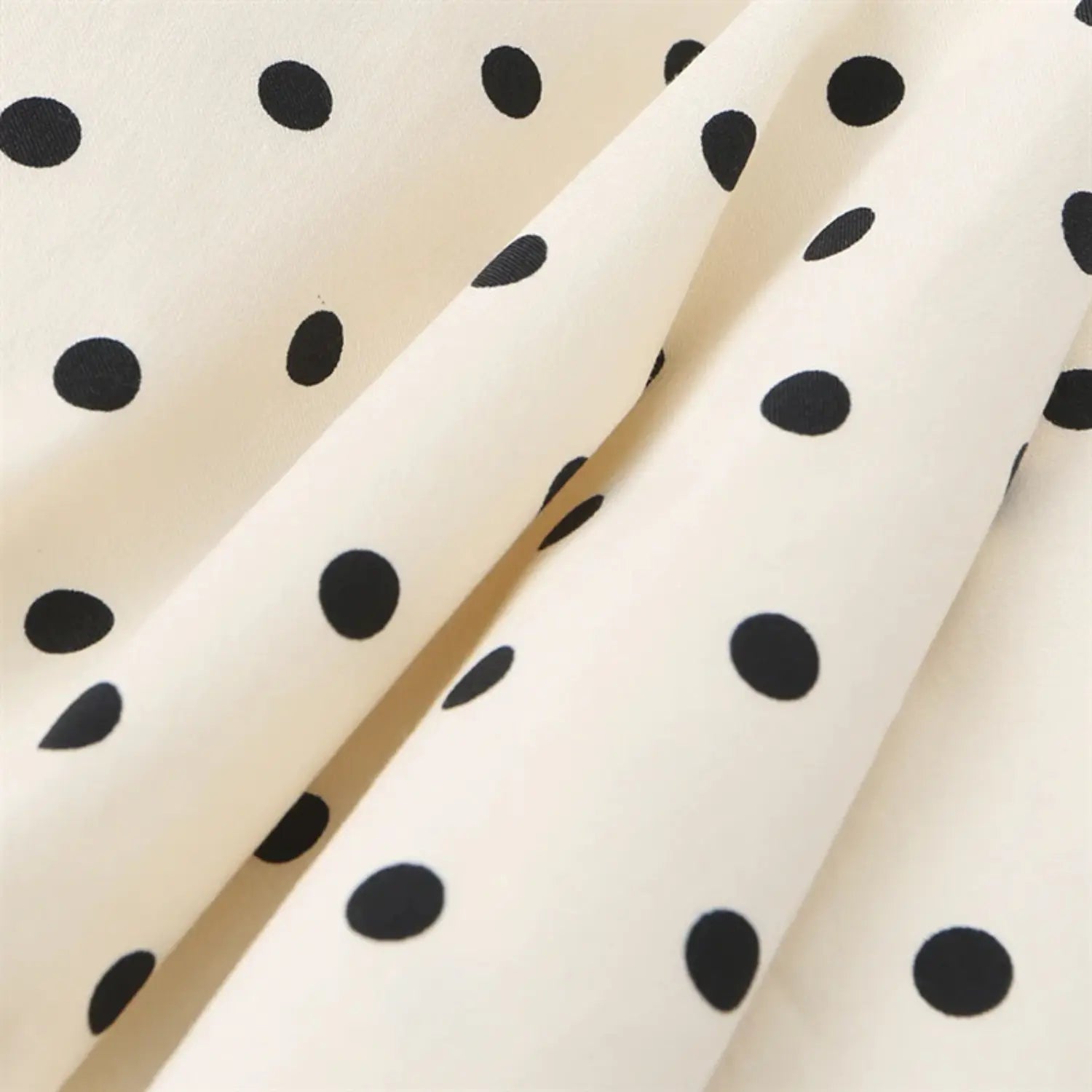 Skirt fabric partial shot, natural soft draping creases, evenly spaced black polka dots, lightweight flowy woven material