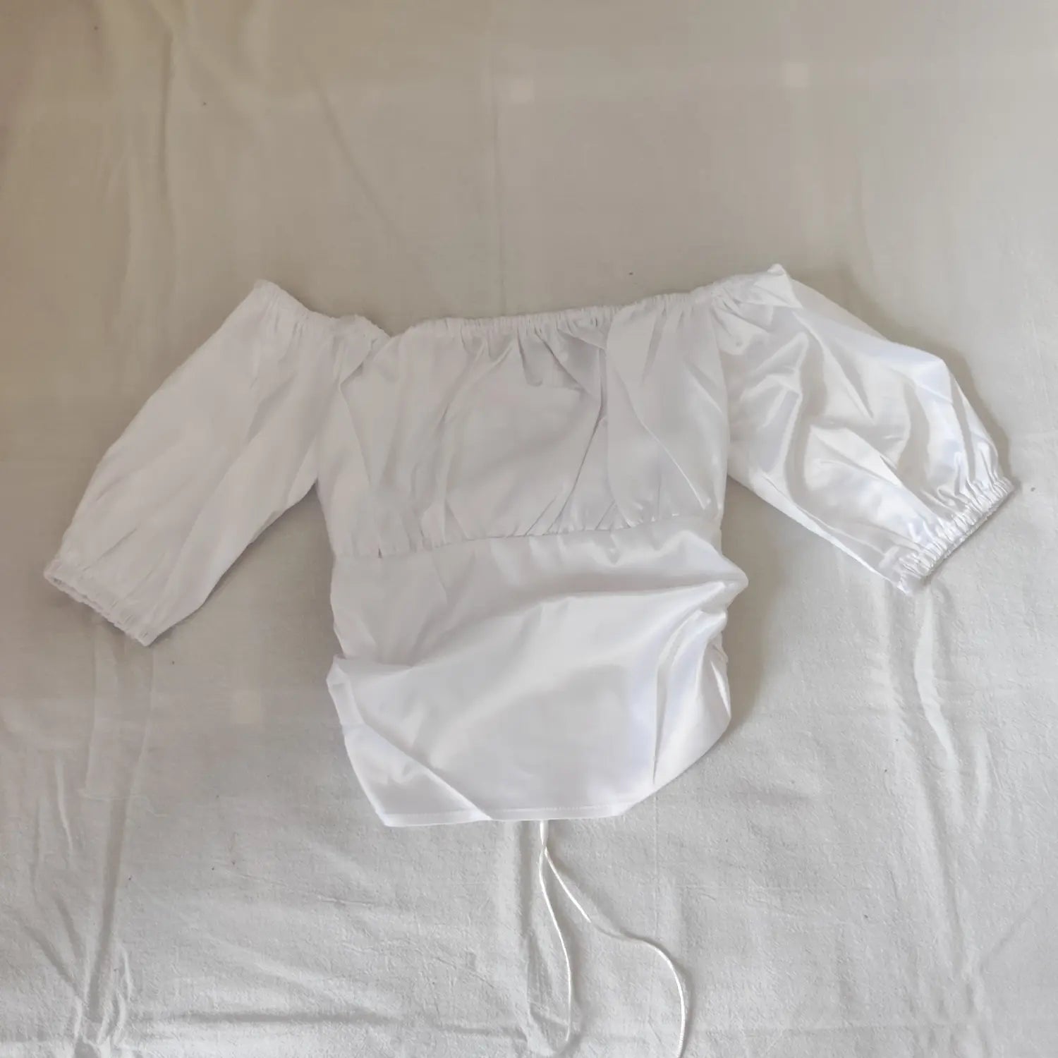 Flat lay back view white satin off shoulder cropped top with side ruched design
