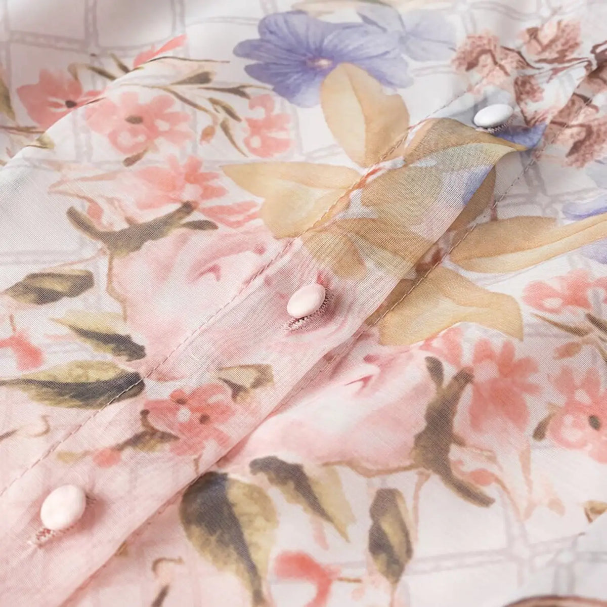 Macro shot of fabric covered buttons on floral bird print chiffon maxi dress, soft sheer printed fabric
