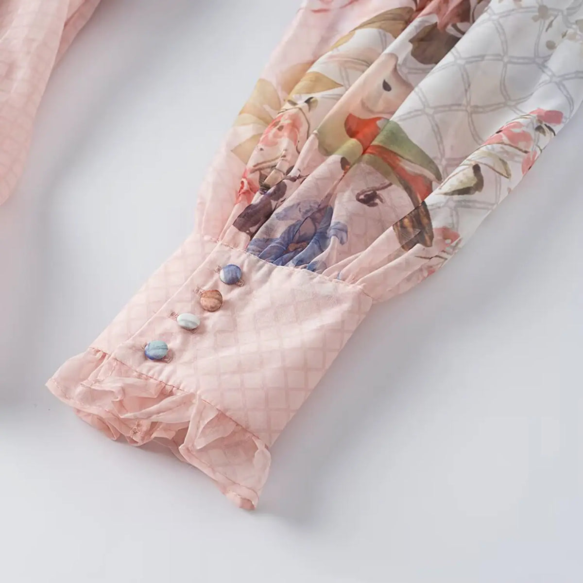 Close-up of balloon sleeve cuff decorated with multi-color buttons and ruffle hem on floral chiffon maxi dress