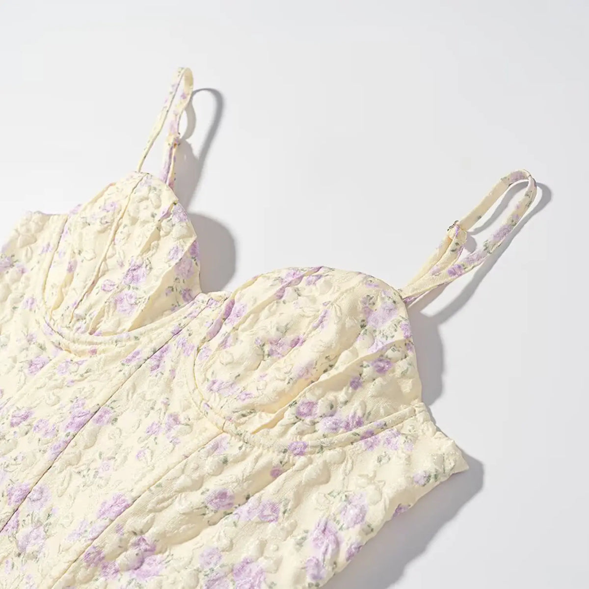 Side closeup of pale yellow purple floral corset cami top, showing adjustable printed thin strap and 3D floral jacquard texture