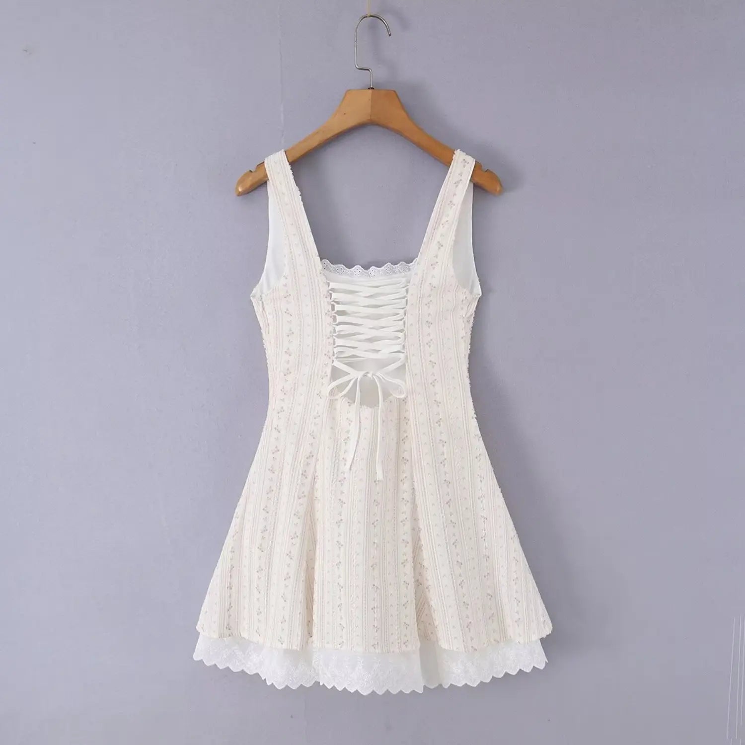 Back hanger shot of slim floral strap mini dress, full corset lace-up cutout back with adjustable fabric tie bow, matching vertical pink floral woven fabric, full cream lining