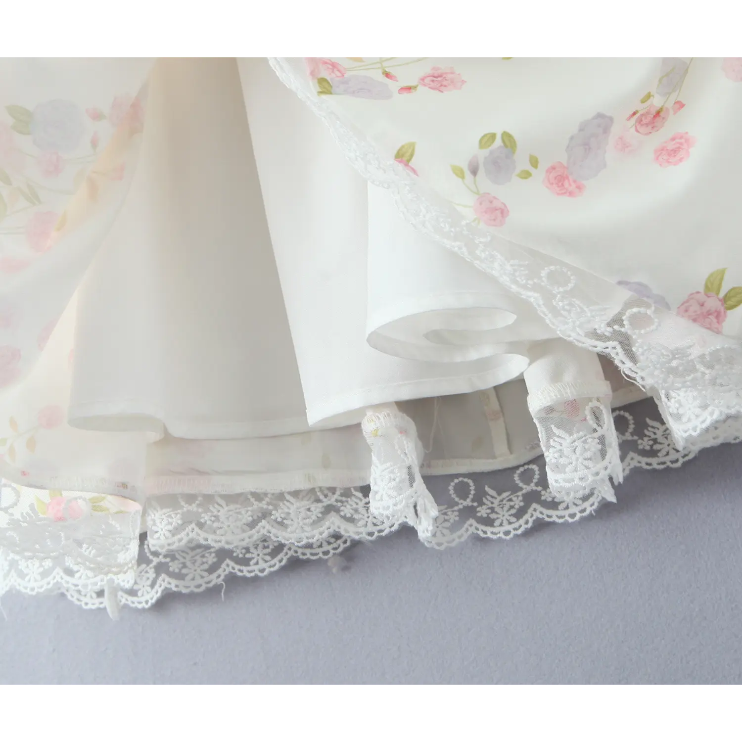 Close‑up view of inner lining and layered hem with white lace trim on cream floral cami mini dress