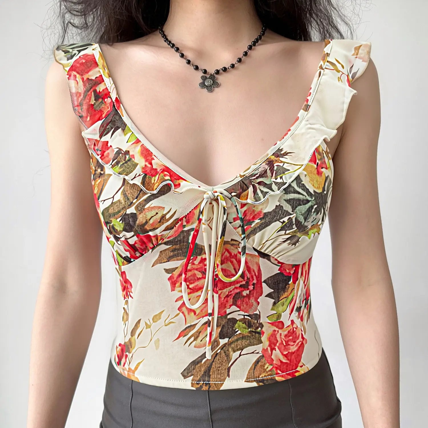 Oil painting rose floral cami real model front wearing shot, V-neck drawstring shape bust ruffle cap sleeves hide arm cropped fit lengthen proportion match black pants feminine daily outfit display
