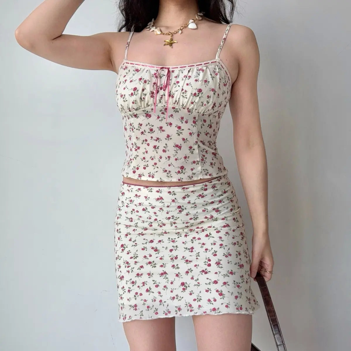 The cream rose-print two-piece set styled with a brown crocodile-pattern handbag.