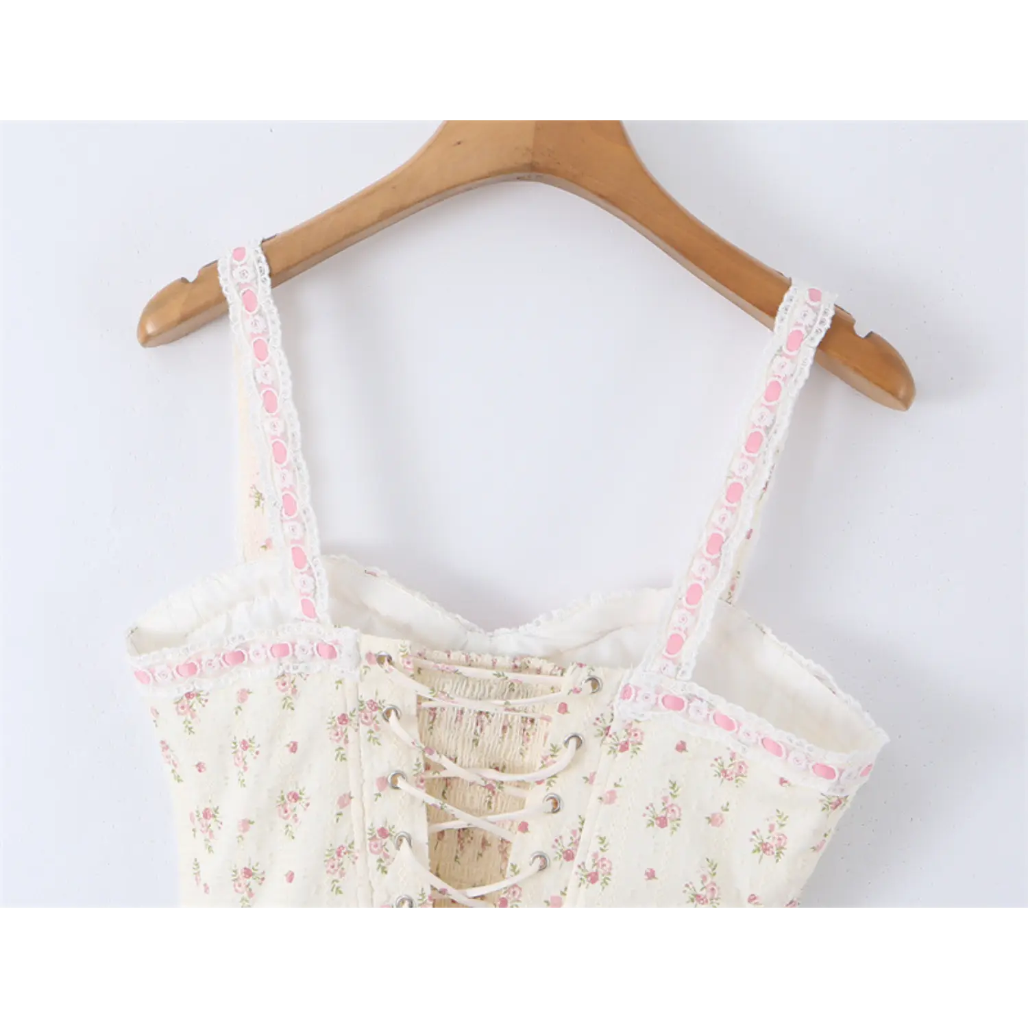 Close-up of the front neckline, lace-trimmed straps and lace-up back on the floral print corset-style camisole top