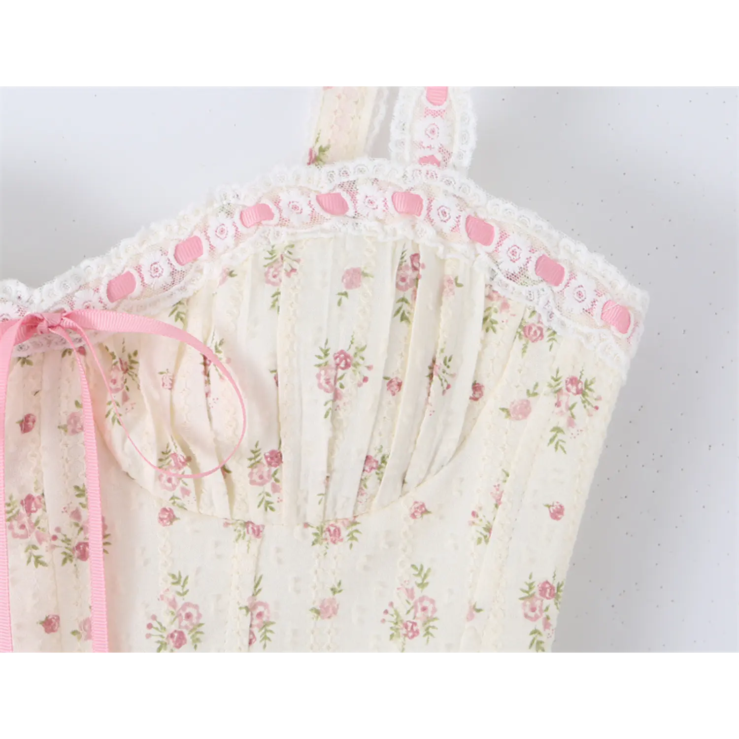 Close-up of the lace-trimmed sweetheart neckline with pink bow detail on the floral print camisole top