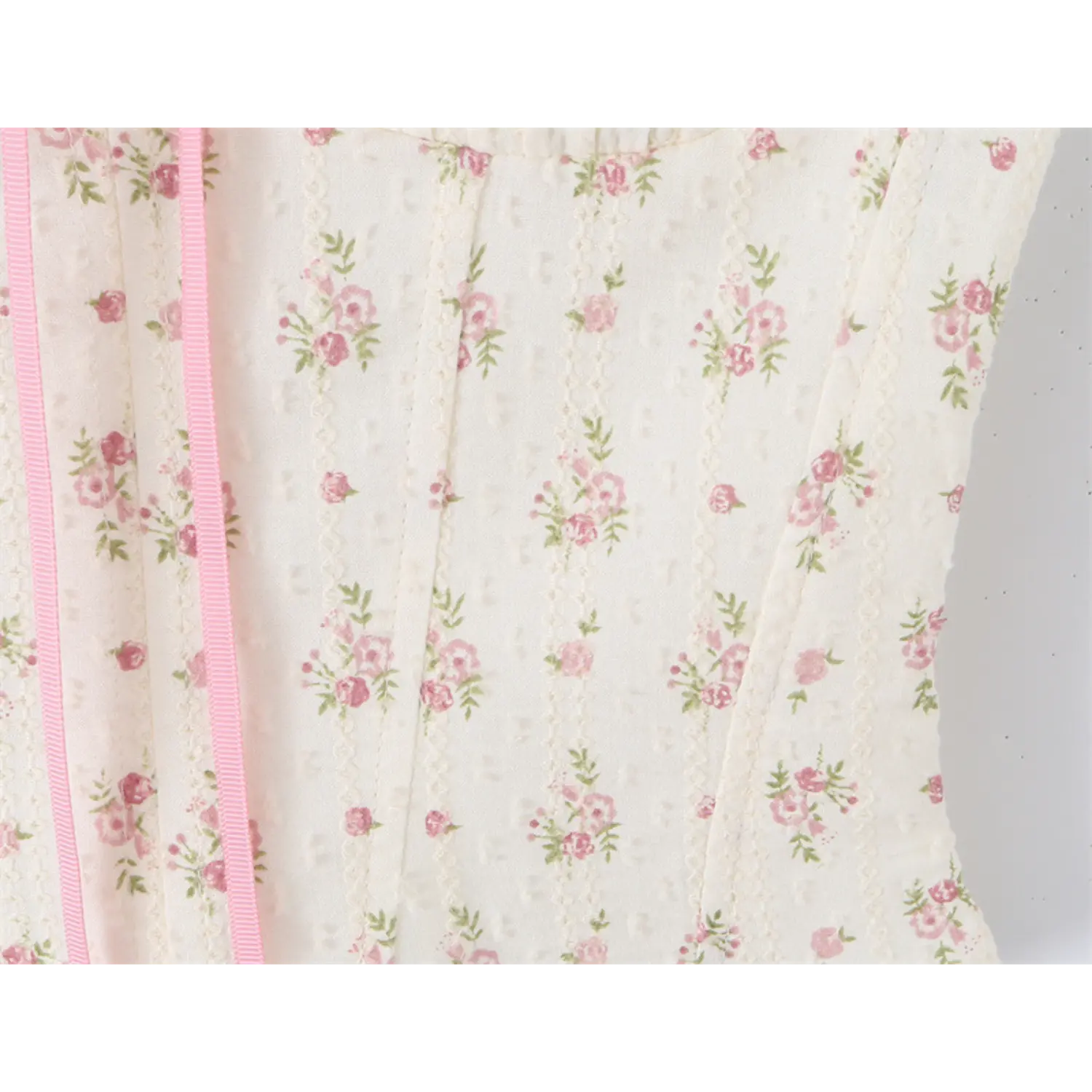  Close-up of the side panel with vertical pink ribbon and floral print on the corset-style camisole top