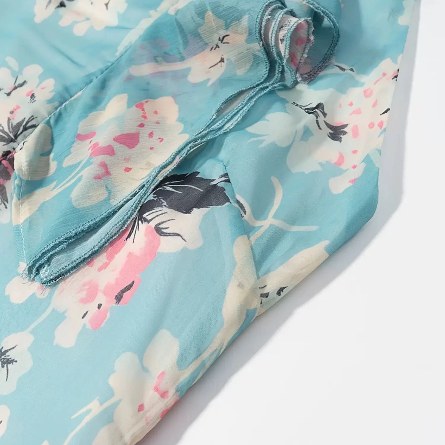 Macro close‑up of chiffon hem edge, finished raw seam on blue floral printed sheer fabric