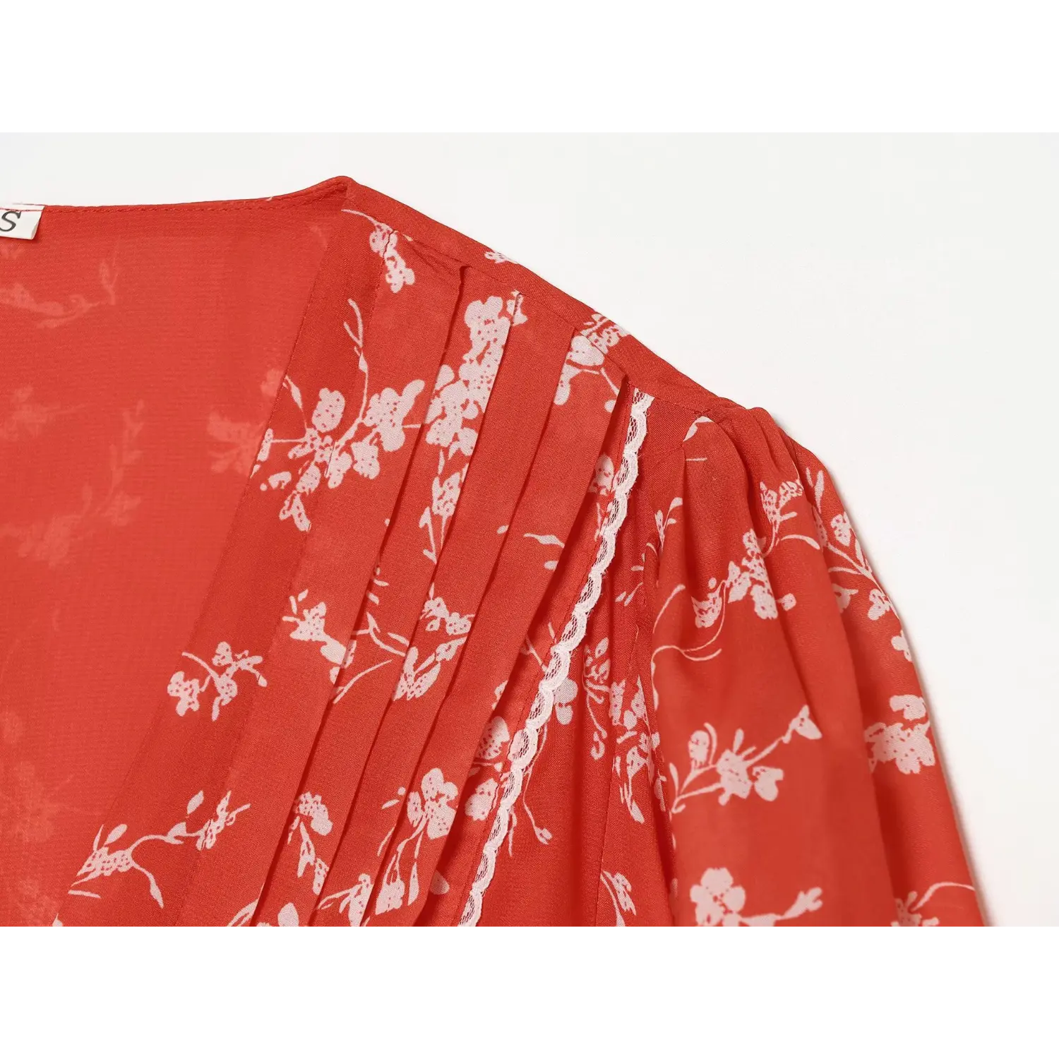 Close-up shoulder view, front pleats and lace trim detail of red white floral chiffon dress