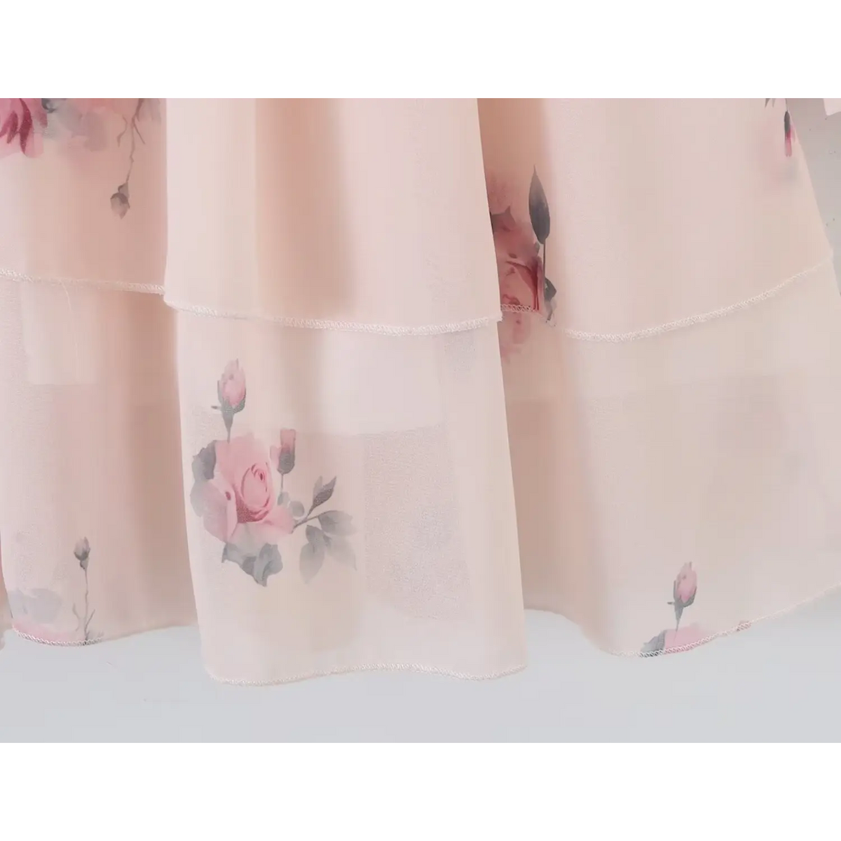 Macro shot of pink rose floral print chiffon fabric on tiered skirt, lightweight semi-sheer texture