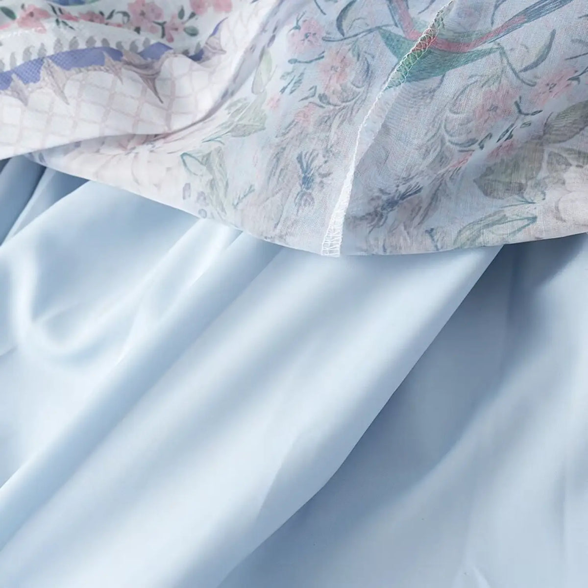 Close-up of chiffon outer fabric and solid inner lining of light blue floral bird print maxi dress