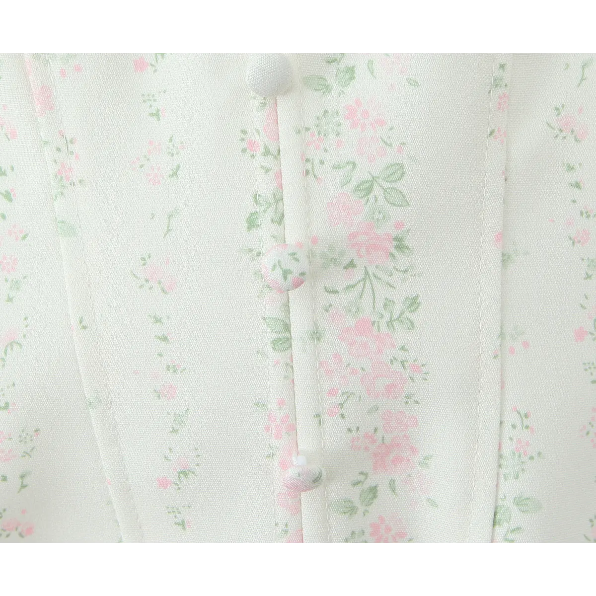 Close-up of the fabric-covered floral buttons on the center front placket.
