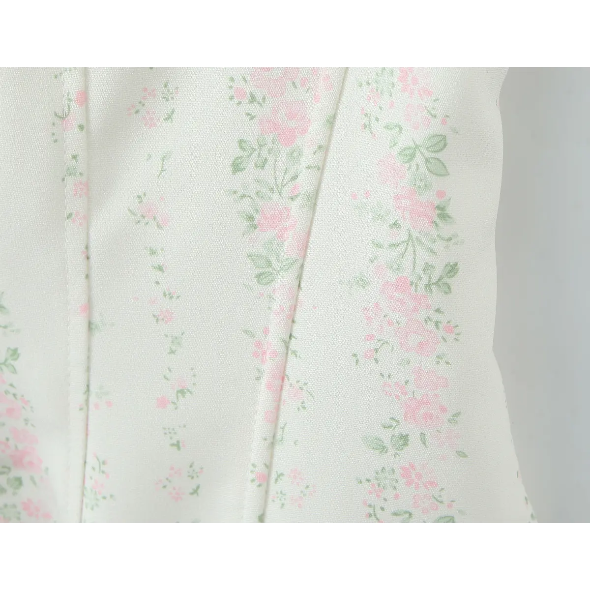 Close-up of the pink rose and green leaf print on the corset-style fabric.