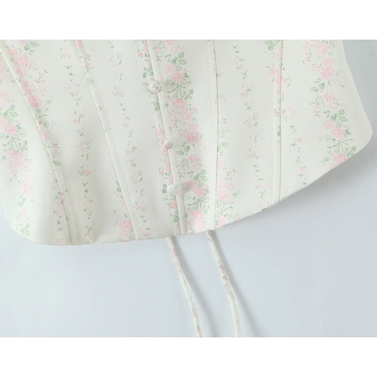 Detail shot of the curved hem with the lace-up ribbon tails hanging down.