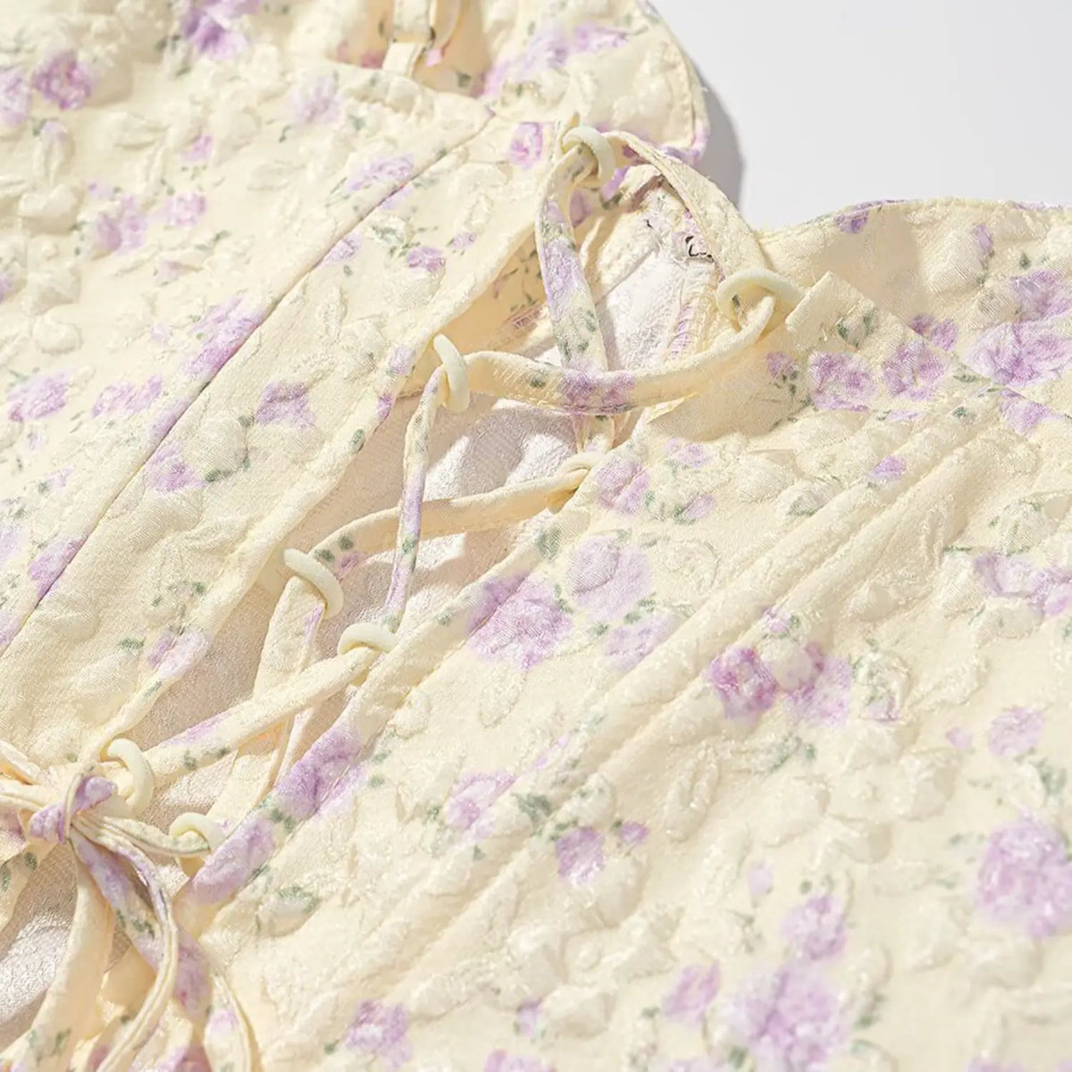 Detailed shot of crisscross lace-up back design of pale yellow purple floral corset cami top