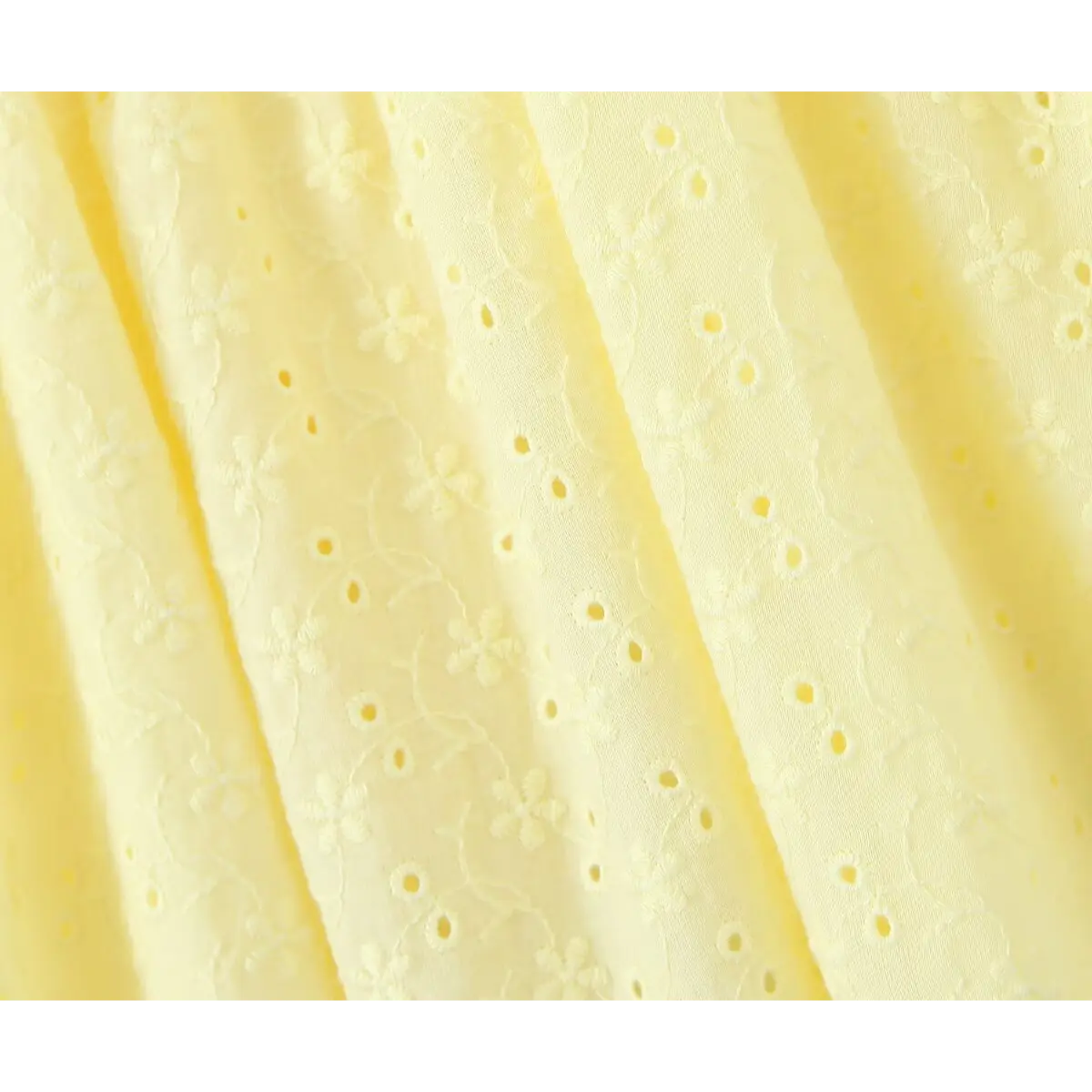 Macro fabric shot, soft cotton with continuous flower embroidery & round hollow eyelet cutout texture.