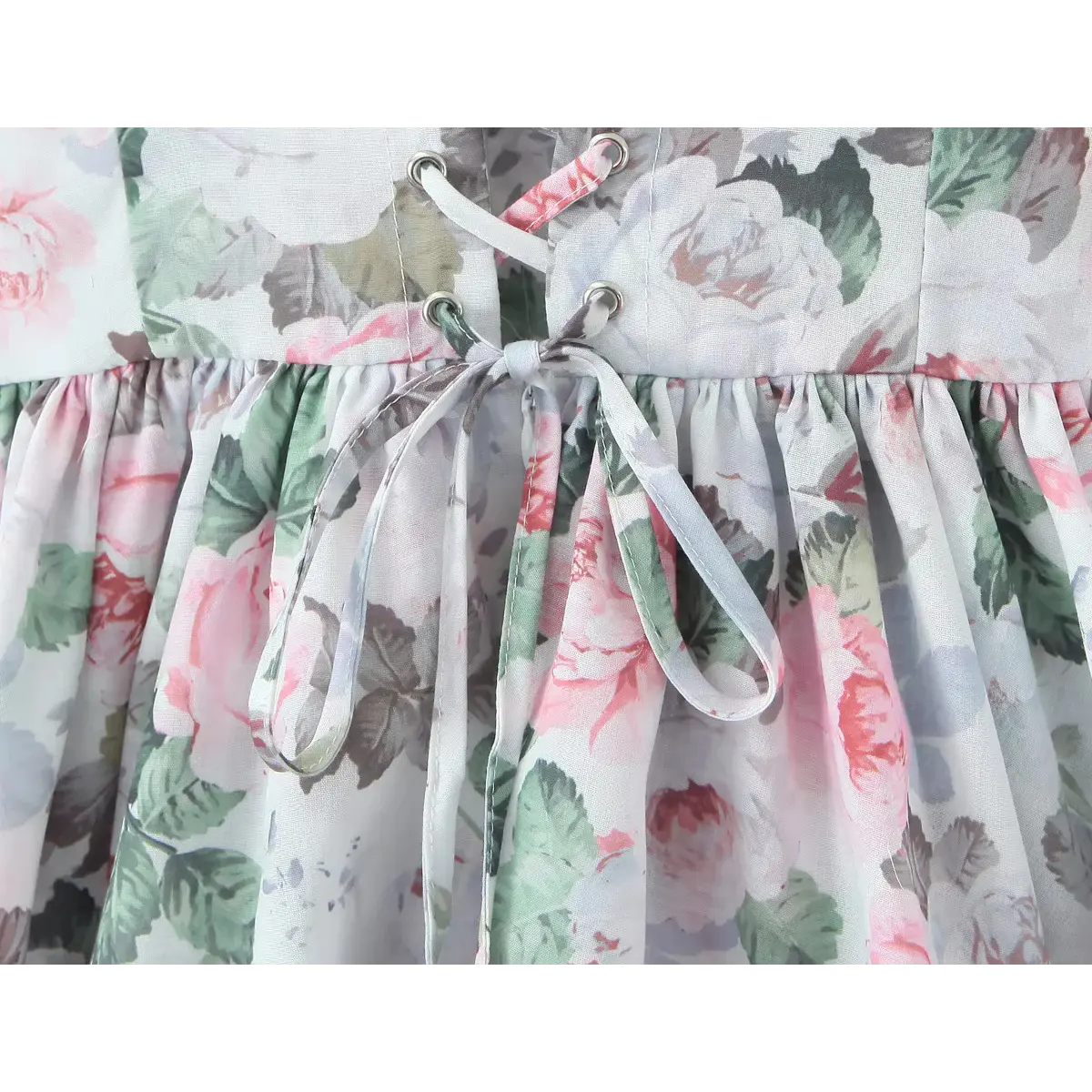 Close-up of the lace-up tie detail at the back waist of a floral print corset dress.