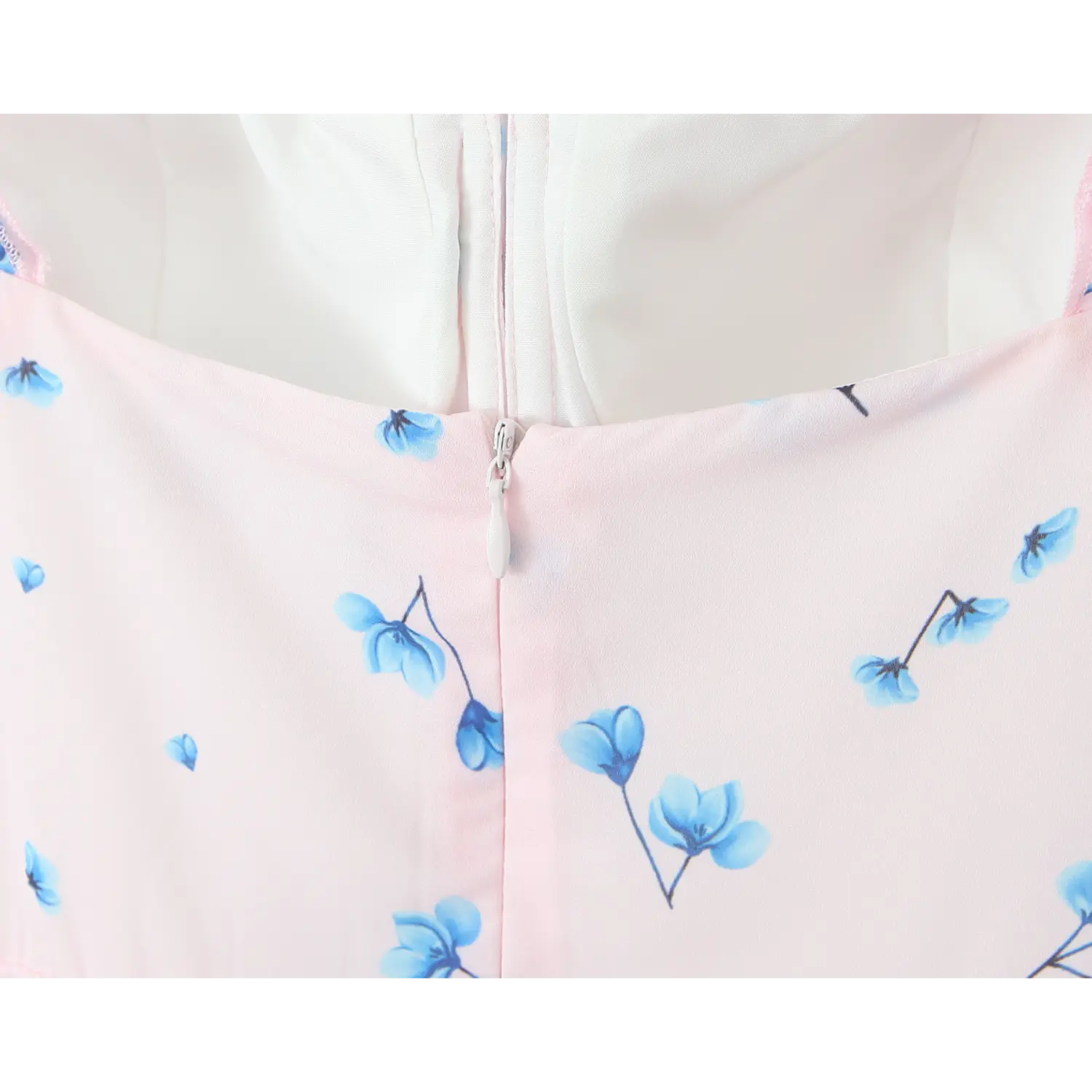 Macro close‑up invisible back zipper, zipper pull detail, pale pink fabric with blue floral print, smooth bodice stitching