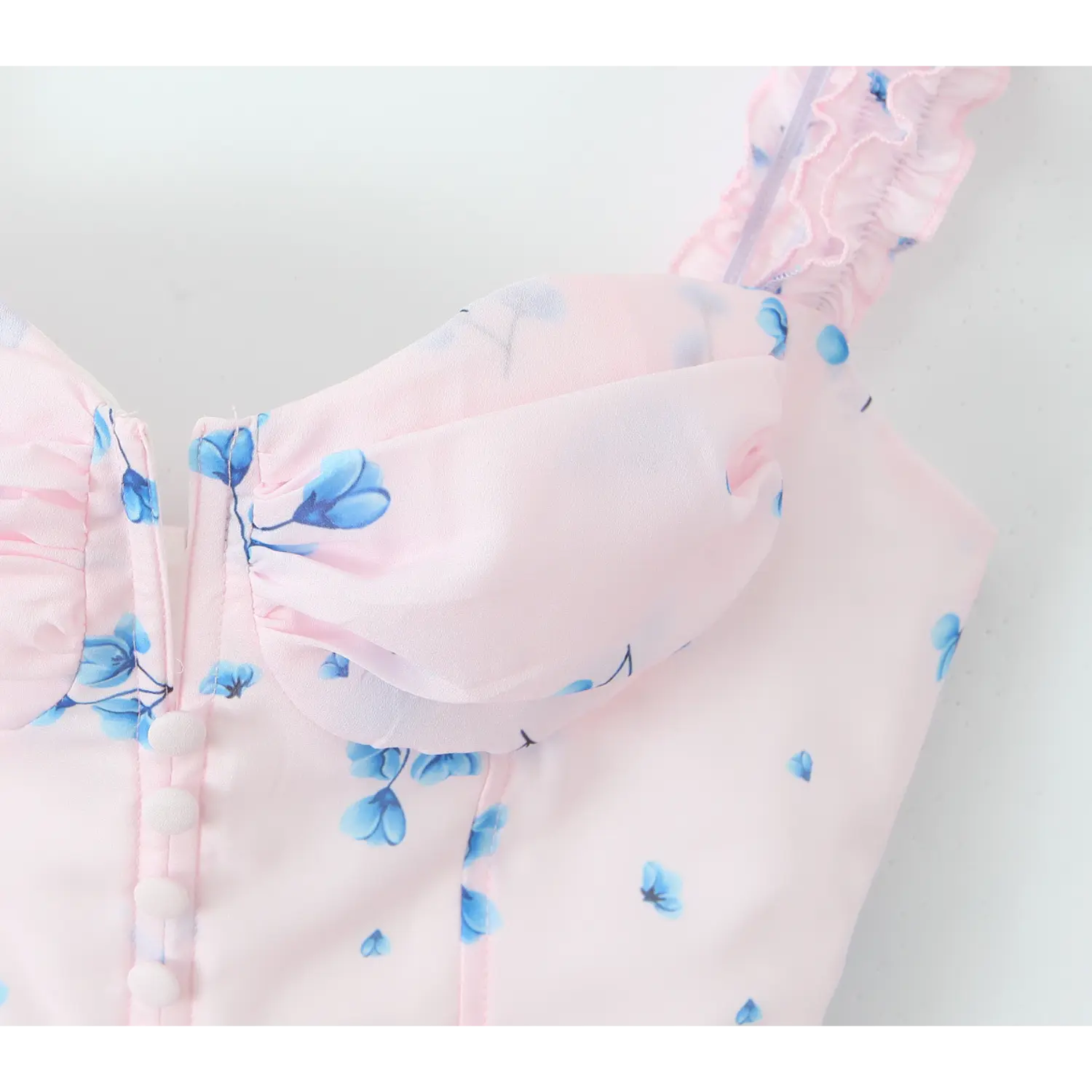 Close‑up of ruched bust bodice, folded chiffon detail, front vertical row of white covered faux buttons, pink blue floral print fabric