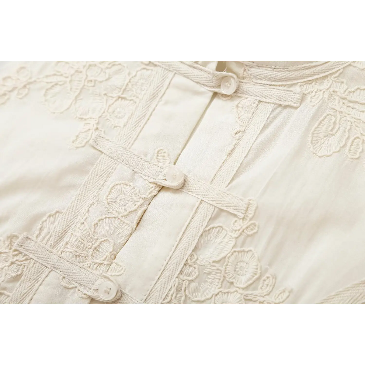Close-up of frog knot button and floral embroidery